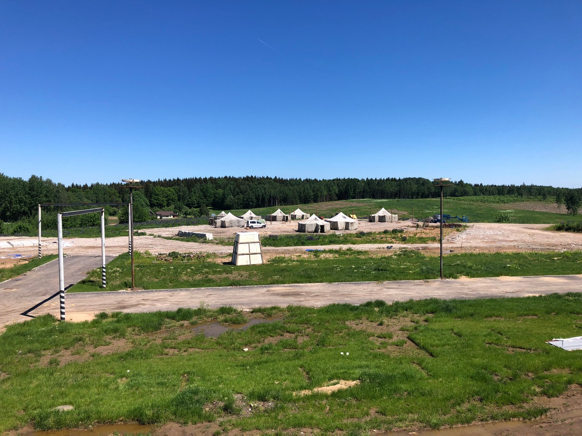 Backlot exterior set with tents, gravel roads and surrounding forest