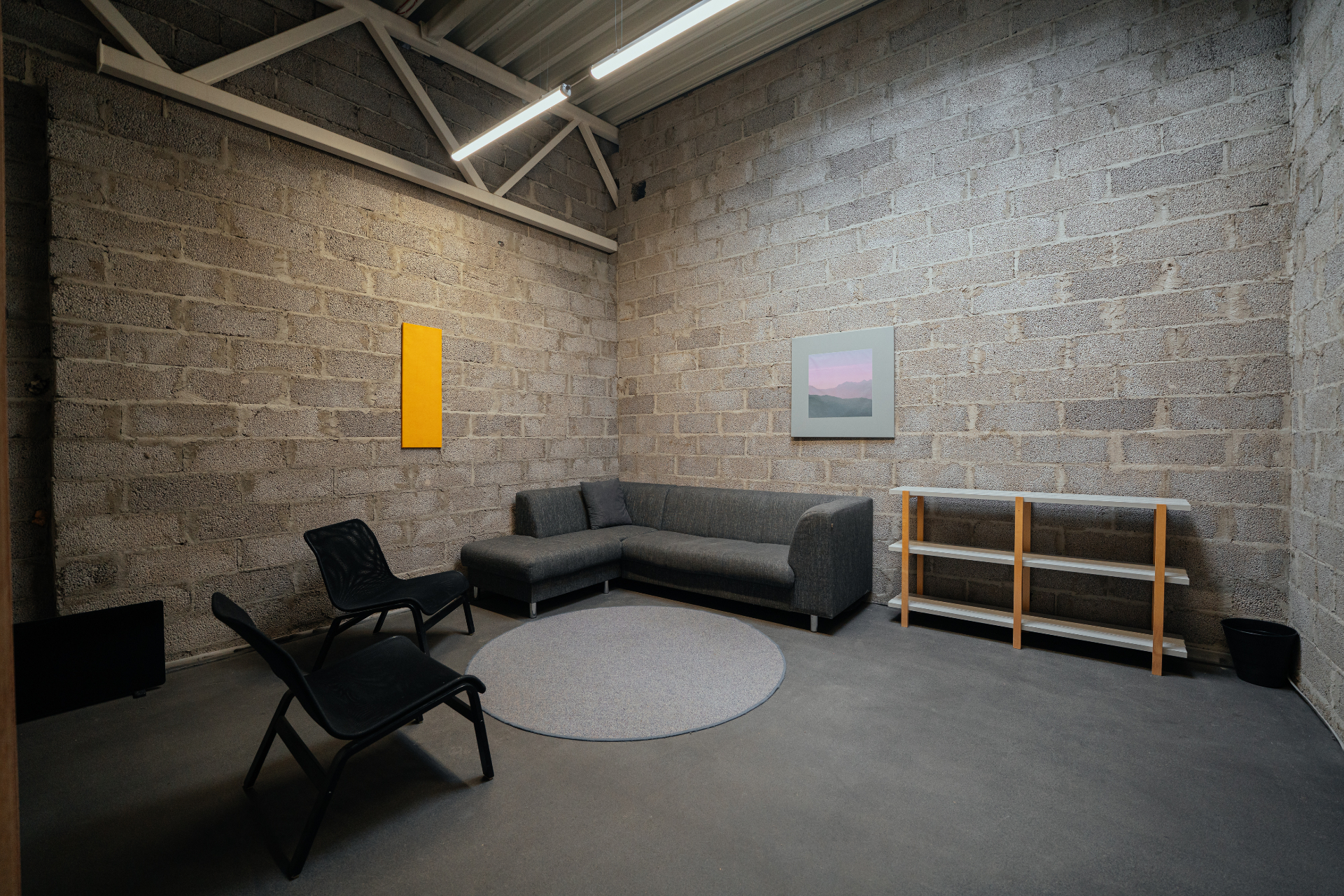 Second floor green room with corner sofa, lounge chairs and artwork on brick walls