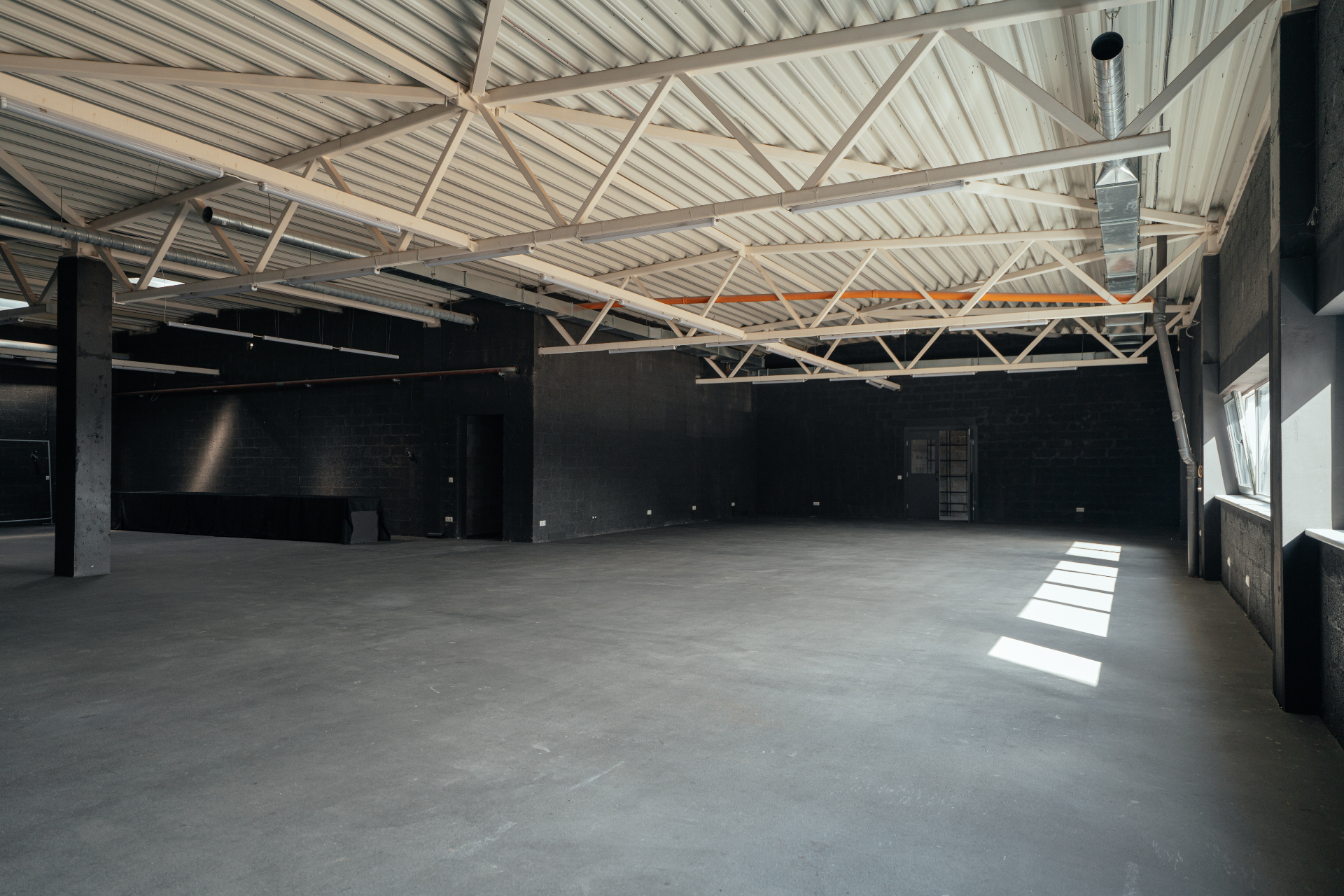 Second floor mini studio with black walls and exposed roof trusses